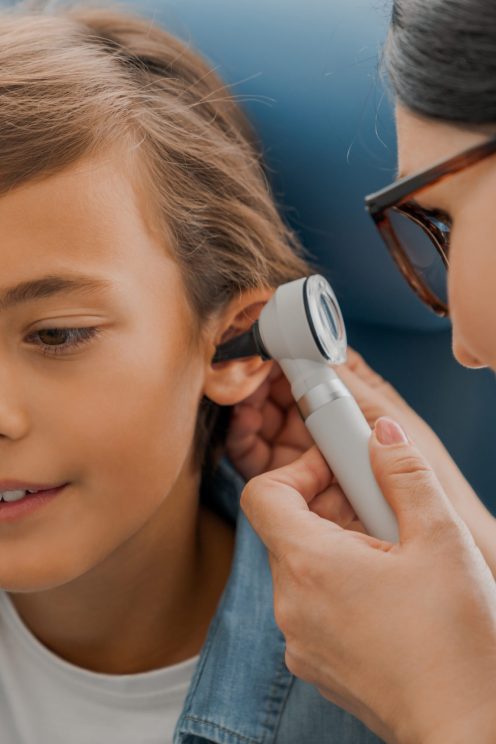 Female doctor examining boy's ear with otoscope