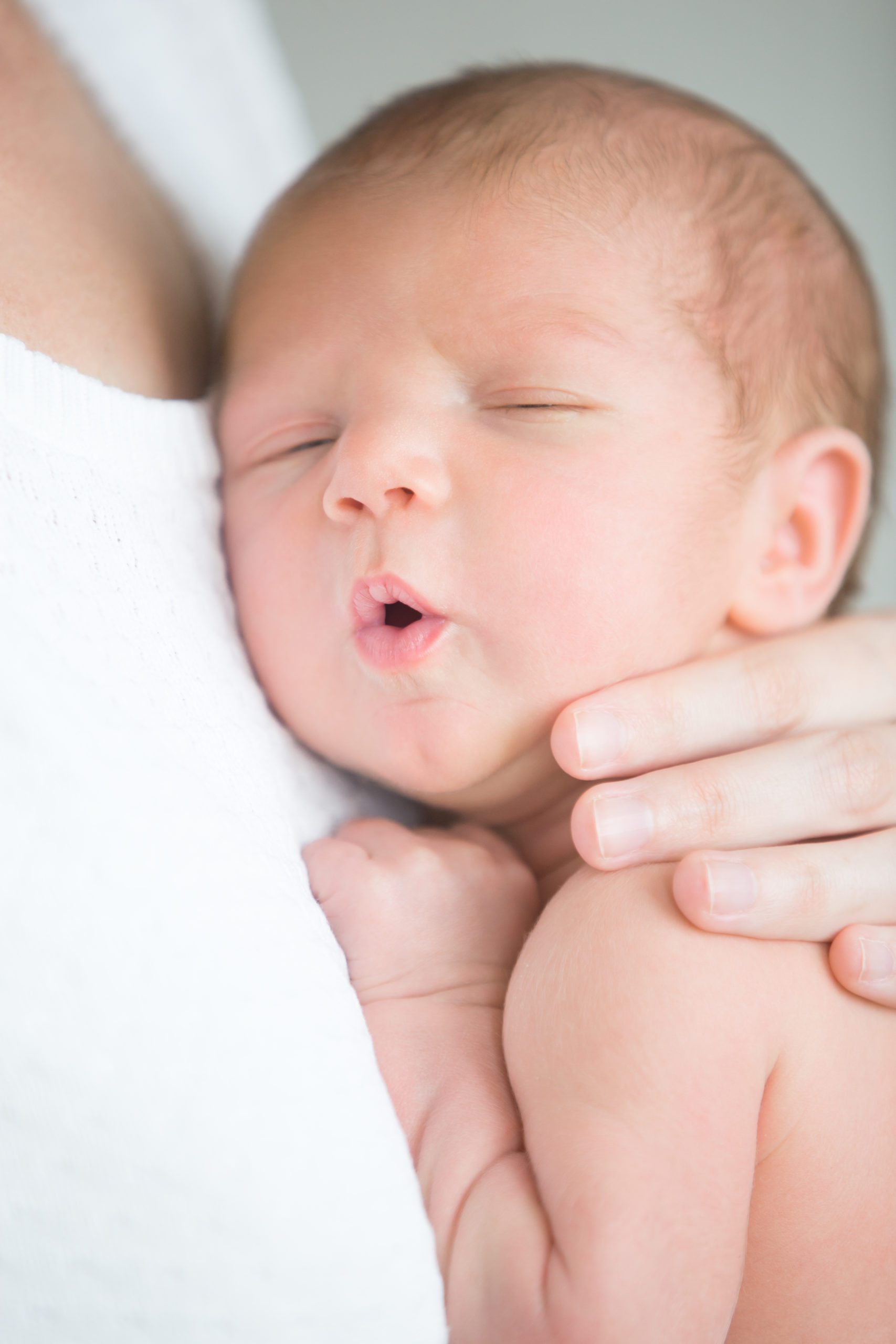 Portrait of a cute newborn hold at mother s breast, his mouth open. Family, healthy birth concept photo, close up