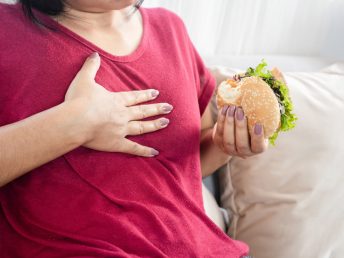 woman having Gastroesophageal reflux disease after eating a burger